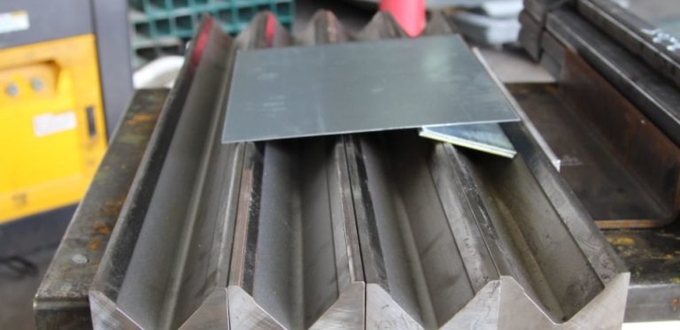 פלטה מברזל מגולוונת אשר חתוכה בדיוק מושלם ונותנת צורה של רבוע, מונחת על גבי משטח ברזל עם שקעים שווים